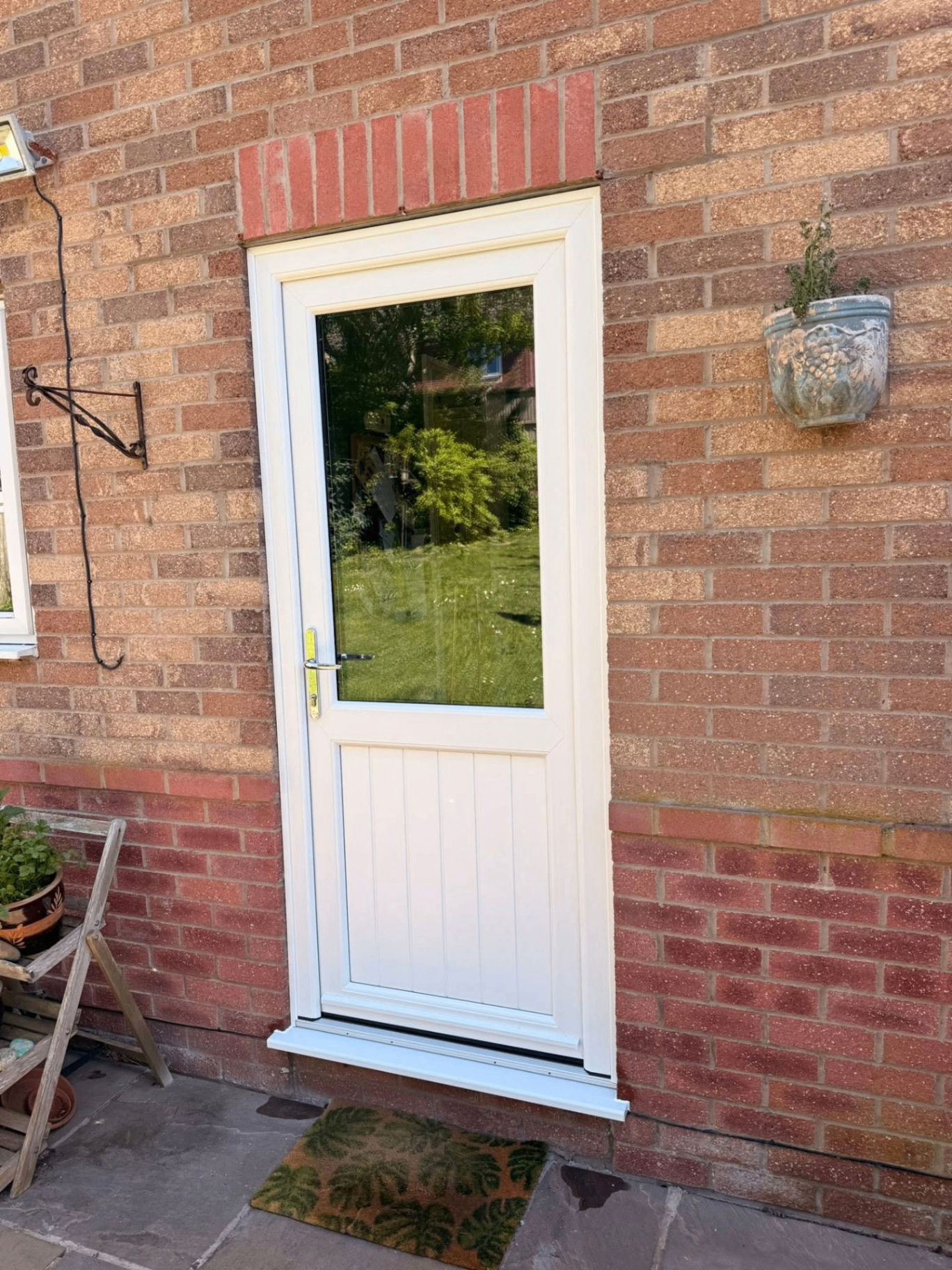 White UPVC back door with half-glazed panel installed on a red-brick Ludlow home