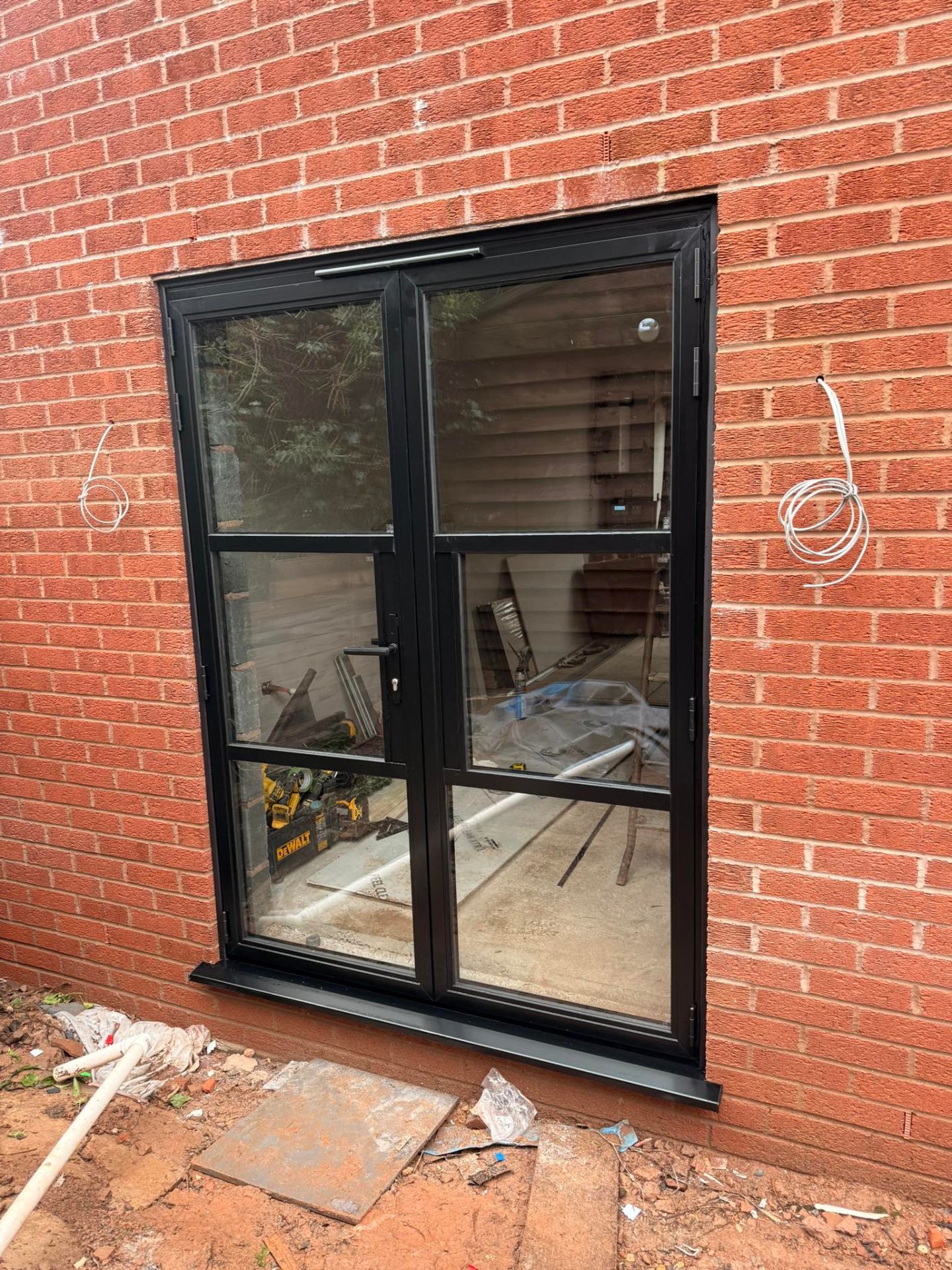 Black aluminium French door installed on a red-brick rear elevation